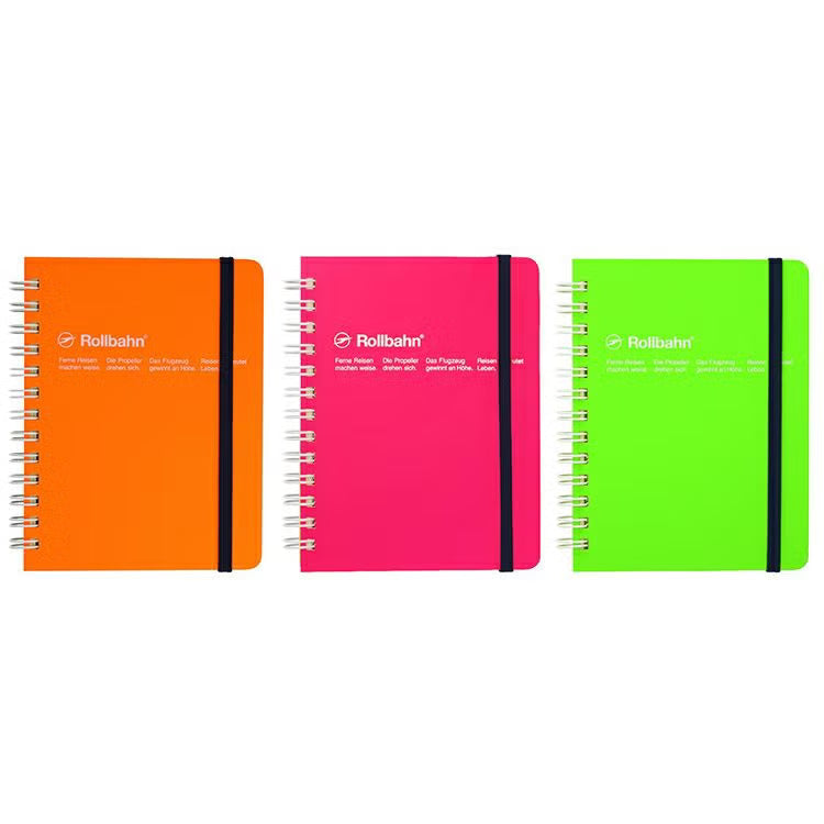 Three spiral-bound Rollbahn notebooks in bright orange, pink, and green, arranged side by side on a plain white background.